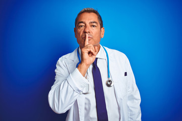 Handsome middle age doctor man wearing stethoscope over isolated blue background asking to be quiet with finger on lips. Silence and secret concept.