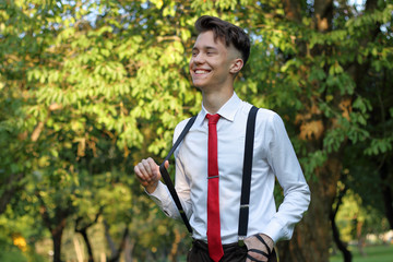 Stylishly dressed young man posing in a park. Pulls the gum from the urine.