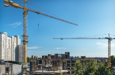 Fototapeta premium A fragment of the city of Kiev, Ukraine. In the foreground are tower cranes over one of the new buildings, as well as constructed residential and office buildings.