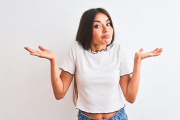 Young beautiful woman wearing casual t-shirt standing over isolated white background clueless and...