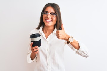 Fototapeta premium Young businesswoman wearing glasses drinking coffee over isolated white background happy with big smile doing ok sign, thumb up with fingers, excellent sign