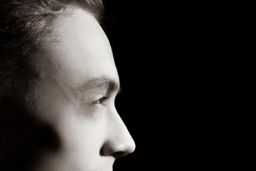 Fragment of the face of a young guy in a dark room