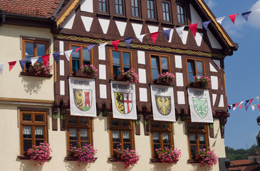 Old historic half timbered house with old flags of Kempten, Memmingen, Isny, Lindau and festival decoration in Schmalkalden, Thuringia, Germany