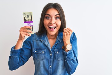 Young beautiful woman holding dollars standing over isolated white background screaming proud and celebrating victory and success very excited, cheering emotion