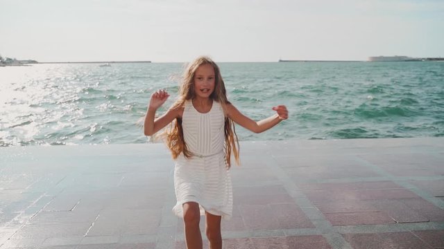 Young girl dancing near sea in white dress