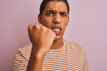 Young handsome arab man wearing striped t-shirt standing over isolated pink background annoyed and frustrated shouting with anger, crazy and yelling with raised hand, anger concept
