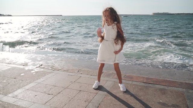 Child girl jumping and dancing near sea