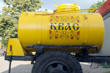 Yellow barrel trailer on black wheels with a drink kvass with the inscription 