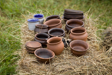 a large number of clay pots lies on a bale of hay