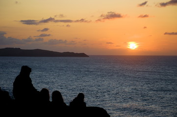 Group of people watching the sunset by the coast in Cantabria, Spain