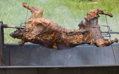 carcass of a young sheep roasting on a spit over low heat