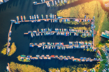 Aerial view of colorful boats and yachts on the sea at sunset in summer. Landscape with pier, motorboats and sailboats, yellow water lilies, lake with blue water. Top view of harbor. Transport