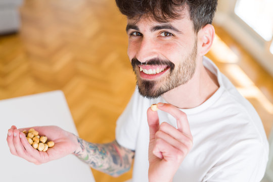 Young man eating hazelnuts, close up of hand with a bunch of healthy nuts