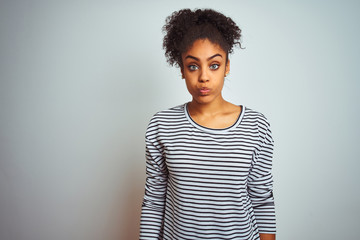 African american woman wearing navy striped t-shirt standing over isolated white background puffing cheeks with funny face. Mouth inflated with air, crazy expression.