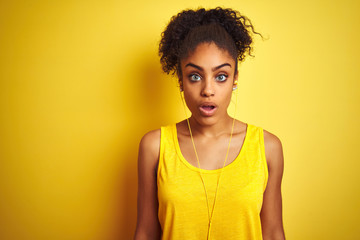 African american woman listening to music using earphones over isolated yellow background afraid...
