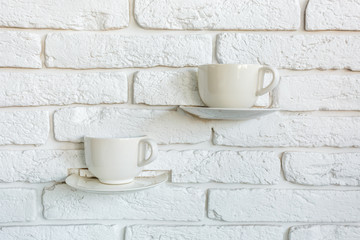 coffee cups as lamp decorations on a white brick wall in modern loft cafe