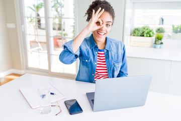 Young african american student woman using computer laptop with happy face smiling doing ok sign with hand on eye looking through fingers