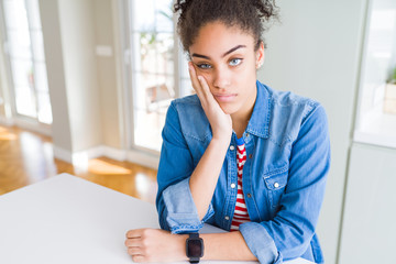 Beautiful young african american woman with afro hair wearing casual denim jacket thinking looking tired and bored with depression problems with crossed arms.