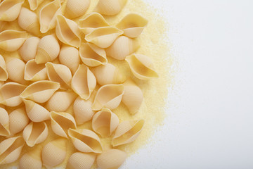 Conchiglie rigate raw pasta and semolina flour on white background, Flat Lay with Copy Space