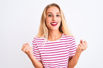 Young beautiful woman wearing pink striped t-shirt standing over isolated white background celebrating surprised and amazed for success with arms raised and open eyes. Winner concept.