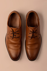 Top view on elegant leather male shoes on beige background