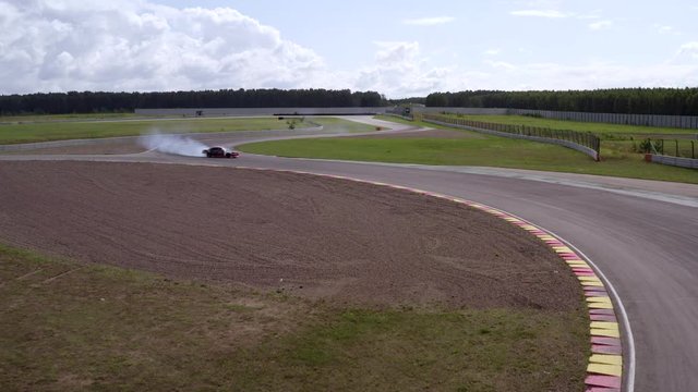 Car drifting on racing track aerial view. Japanese car drifting with smoke from burning tires on speed track. Professional driver drifting car on asphalt track
