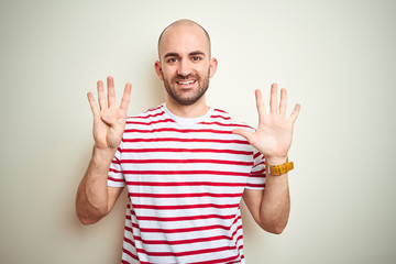 Young bald man with beard wearing casual striped red t-shirt over white isolated background showing...