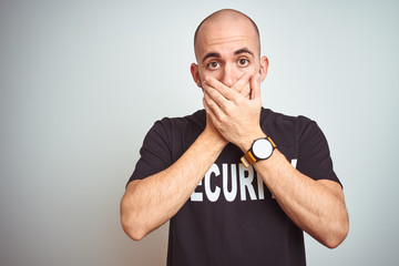 Young safeguard man wearing security uniform over isolated background shocked covering mouth with...
