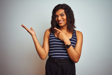 Transsexual transgender woman wearing striped t-shirt over isolated white background amazed and smiling to the camera while presenting with hand and pointing with finger.