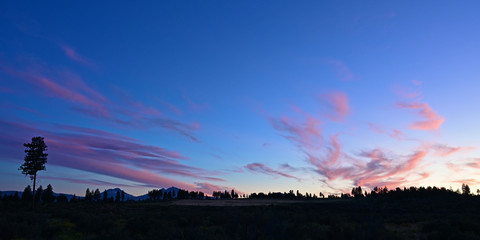 Sunset clouds over Three Sisters volcanoes and town of Sisters, Oregon on summer evening.
