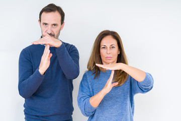 Beautiful middle age couple in love over isolated background Doing time out gesture with hands,...