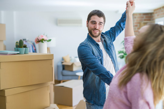 Young couple dancing celebrating moving to new apartment around cardboard boxes