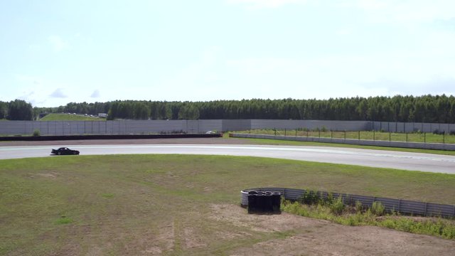Black car riding on speed track view from drone. Sport car drifting on turn training track. Aerial view japanese car driving with driftage on racing road
