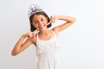 Beautiful child girl wearing princess crown standing over isolated white background smiling cheerful showing and pointing with fingers teeth and mouth. Dental health concept.