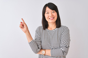Young beautiful chinese woman wearing black striped t-shirt over isolated white background with a big smile on face, pointing with hand and finger to the side looking at the camera.