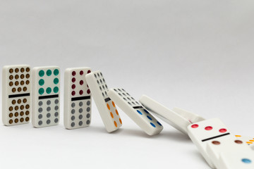 Line of colorful falling dominos on white background.