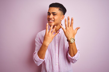 Young brazilian man wearing shirt standing over isolated pink background showing and pointing up...