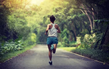 Gordijnen Female runner running at summer park trail . Healthy fitness woman jogging outdoors. © lzf