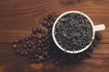 Cup with tea and coffee grains on wooden table
