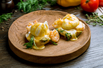 eggs Benedict with shrimps and avocado on beautiful board