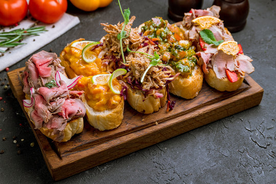 assorted bruschett on the Board on black concrete table