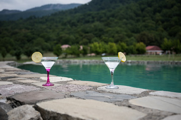 Glass of martini cocktail at swimming pool with ocean and palm tree background. A glass of blue martini cocktail welcome drink bar.Selective focus. season and holidays concept.