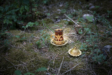 Eastern black tea in glass at the forest. Eastern tea concept. Armudu traditional cup. Green nature background.
