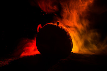 Halloween theme with pumpkin against smoky dark background. Empty space for text
