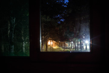 House in the forest at night. View from window. Selective focus