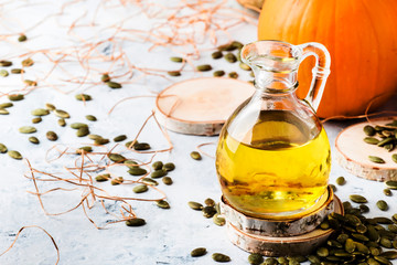 Pumpkin seeds oil in glass jug on white rustic background, copy space, selective focus
