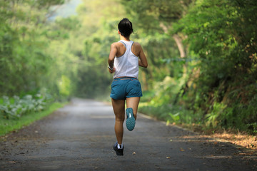 Female runner running at summer park trail . Healthy fitness woman jogging outdoors.