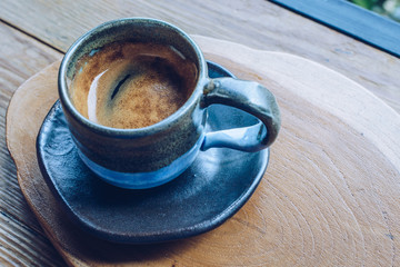 A cup of hot espresso shot on the wooden table. Espresso is a full-flavored It is made by forcing pressurized, hot water through very finely ground coffee beans. 