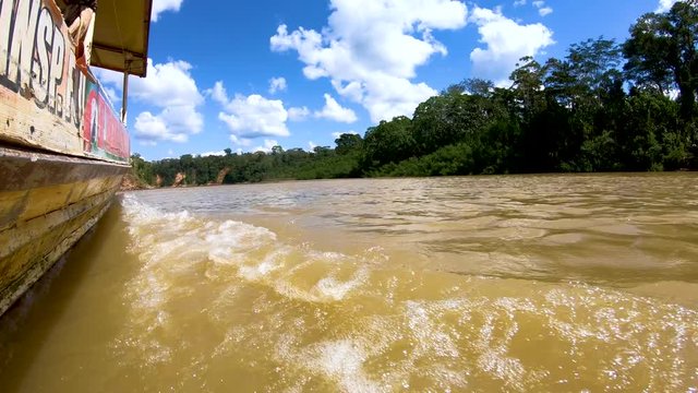 Close up of water splashing at port side, left-hand side, of a moving boat in the jungle of Madre de Dios, Peru.  Sailing during midday in the river. Water splashing in the lens of the camera.