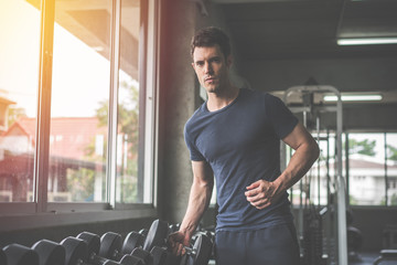 Handsome weightlifter lifting bench press working out with dumbbell in the gym
